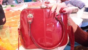 Red handbag with hand and red nails