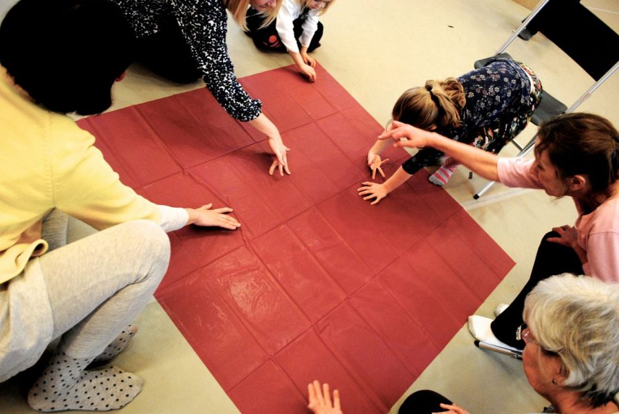 Hands around a large red square, people crouching