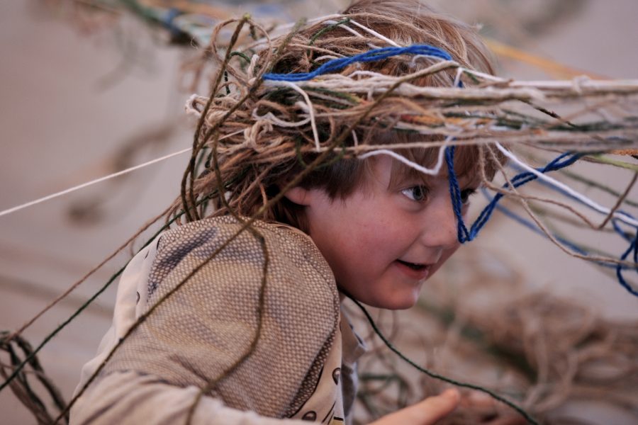 Young boy with woolen threads around his head