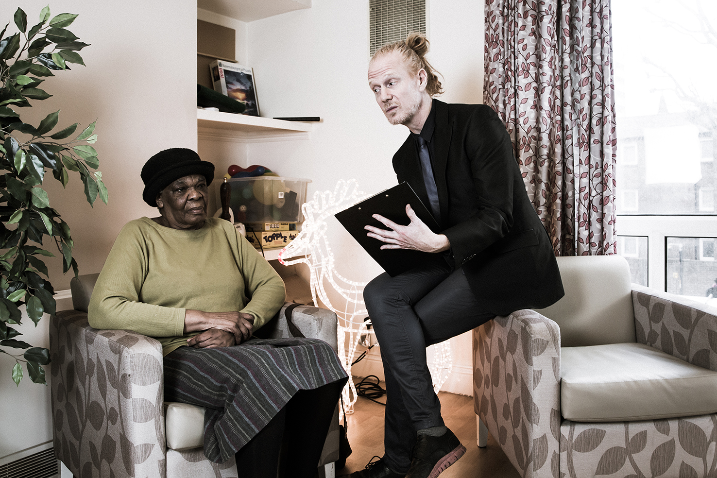 man sitting on armchair reading, woman listening