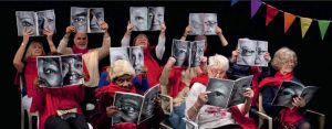 older people in red shirts with photographs held up