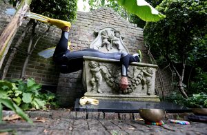 artist lying on a concrete sculpture in a garden