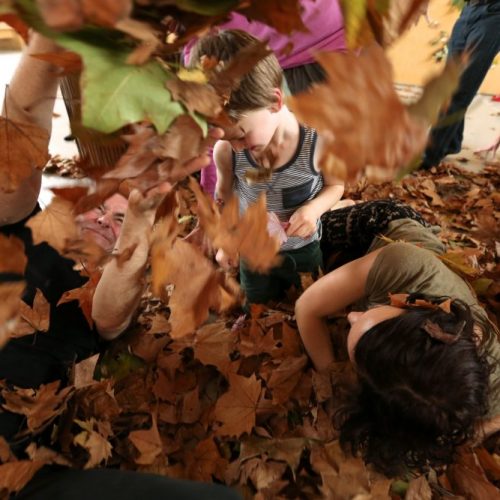 young children playing in dry leaves
