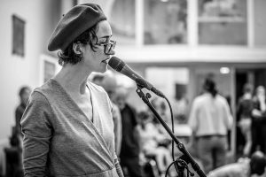 artist speaking into microphone wearing beret