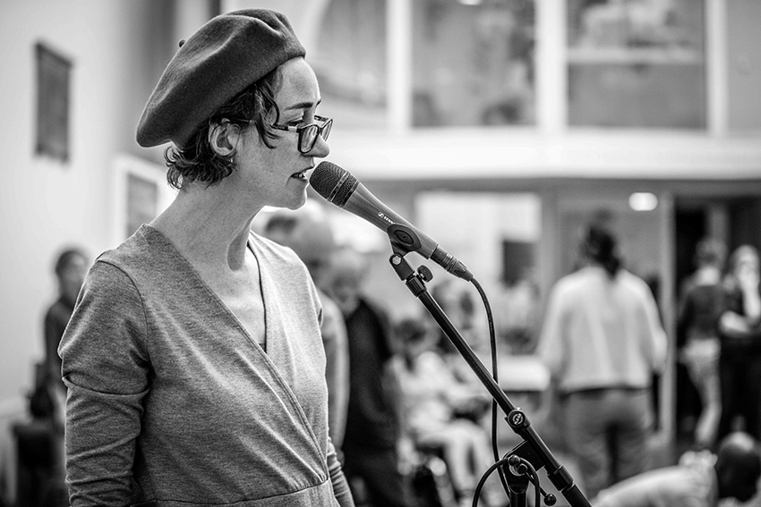 artist speaking into microphone wearing beret