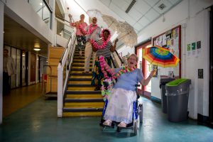 women with umbrellas and feather boas laughing on the stairs