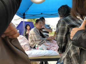 woman in bed on street under umbrella