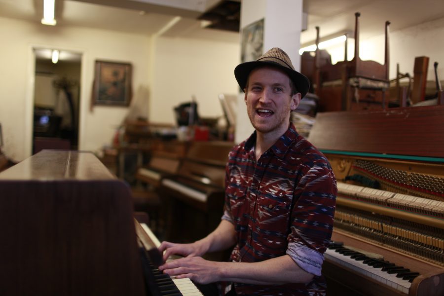 man playing piano in a hat