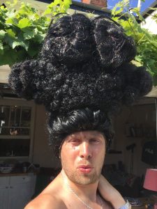 Man waering large black wig