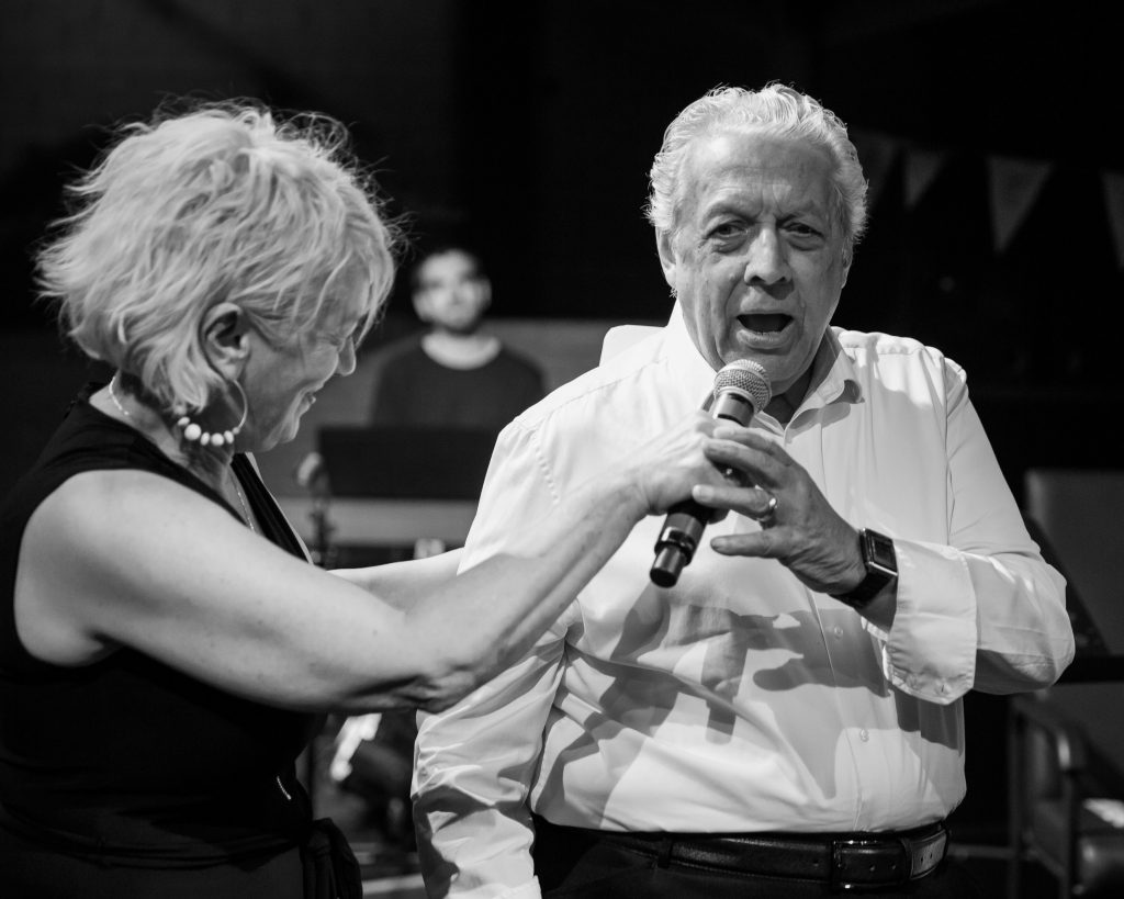 man singing with a microphone held by woman