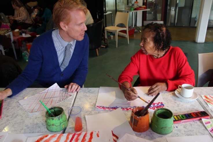 Artist chatting to elder while painting