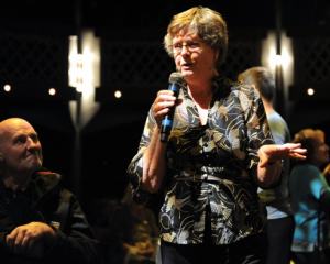 older woman holding microphone singing 