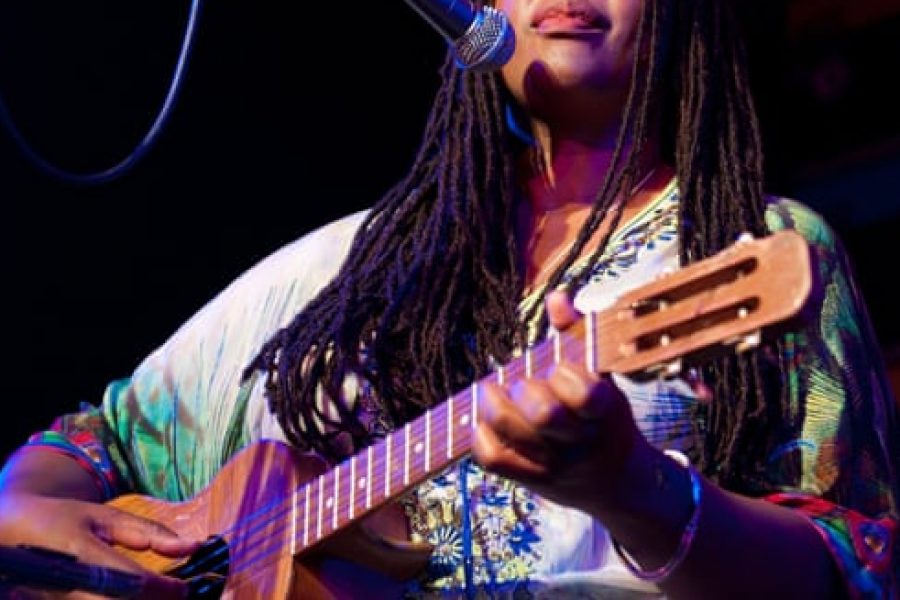 black african woman with guitar singing on stage