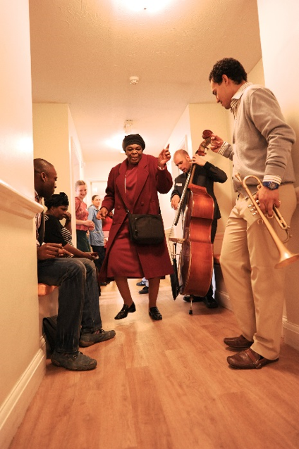 women dancing in care home corridor with a group of musicians