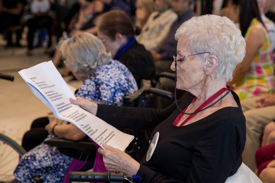 woman sitting in a wheelchair in a group reading a song sheet