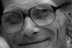 close up of a mans face with glasses, he is smiling