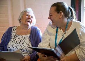 older woman and carer smilinga nd singing together