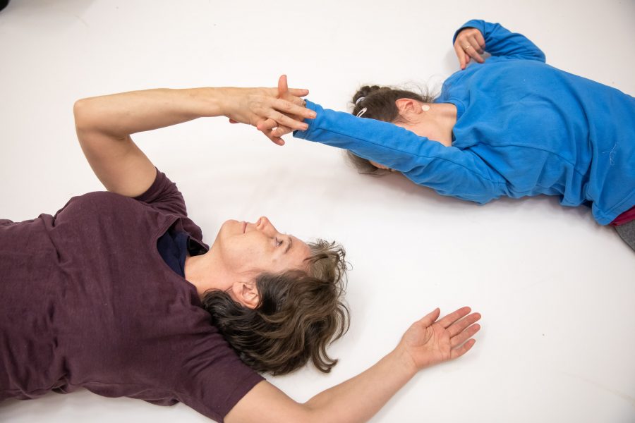 two people making shapes lying on the floor