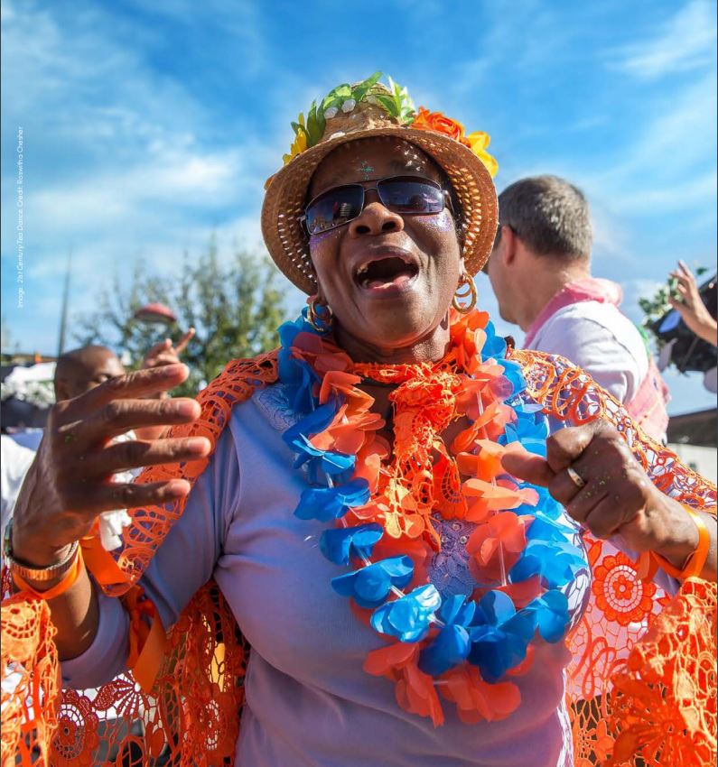 woman with hat and garlands smiling outside