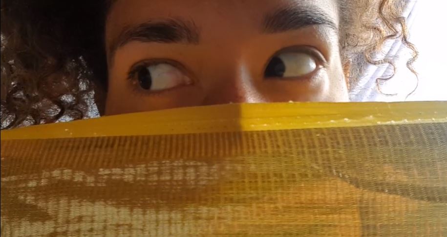 a womens eyes with face covered by gold cloth