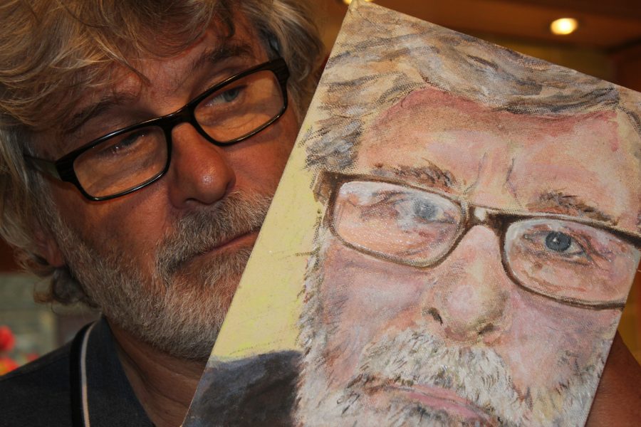 image of a man holding a painting of himself