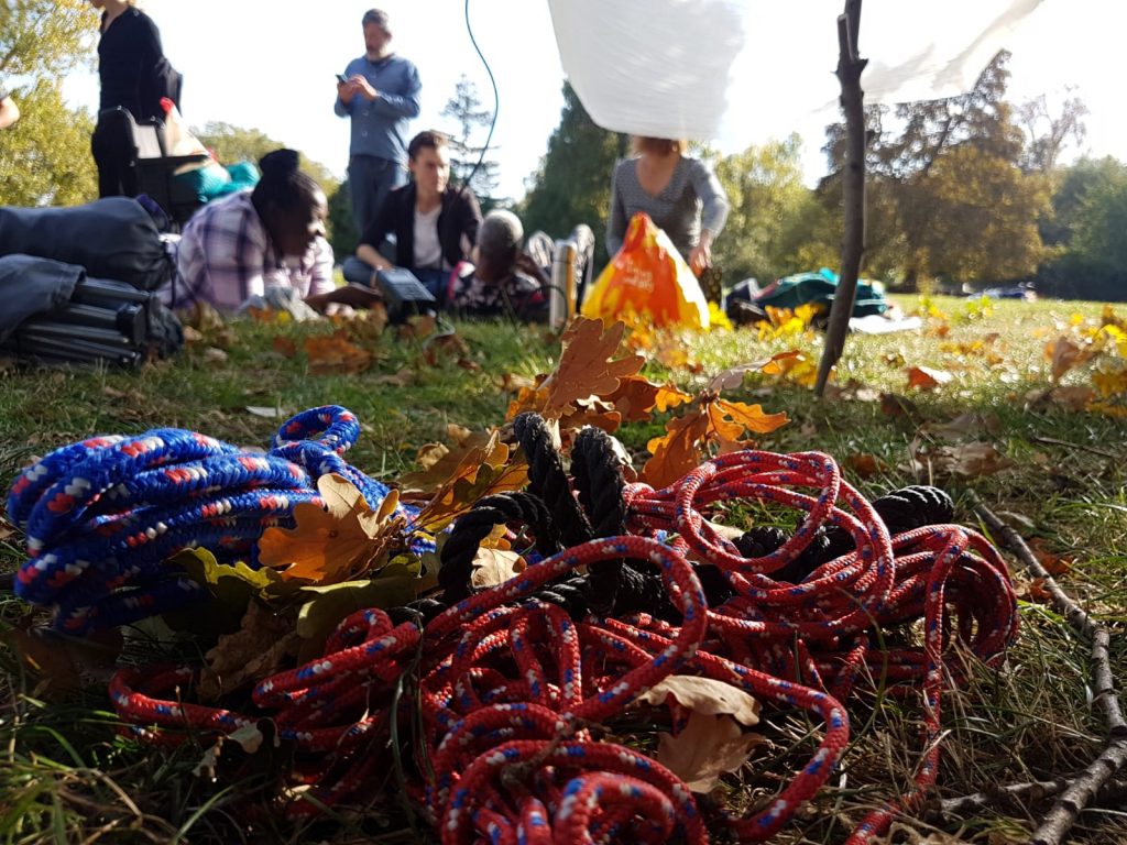 people in the distance in a park. a pile of rope on the grass.