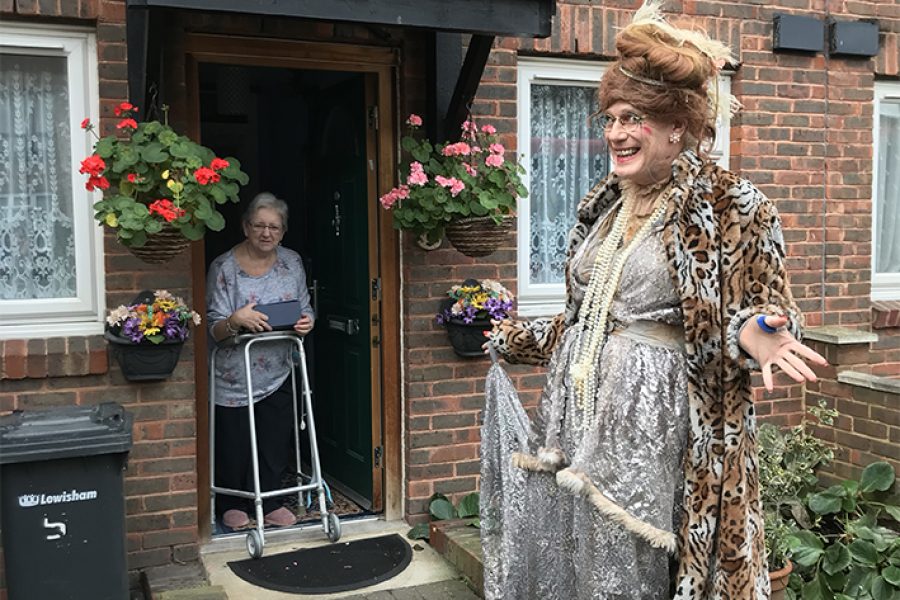 man dressed up as a woman visitng a doorstep of elderly person for fun