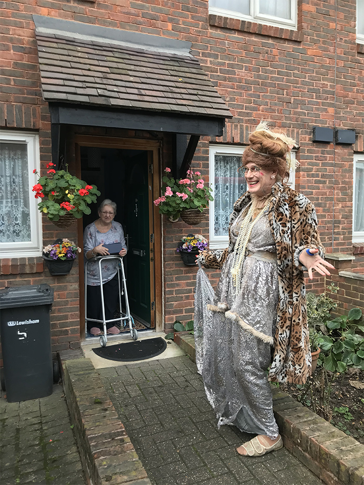 man dressed up as a woman visitng a doorstep of elderly person for fun