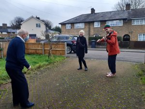 two musicians playing to an older person on the doorstep