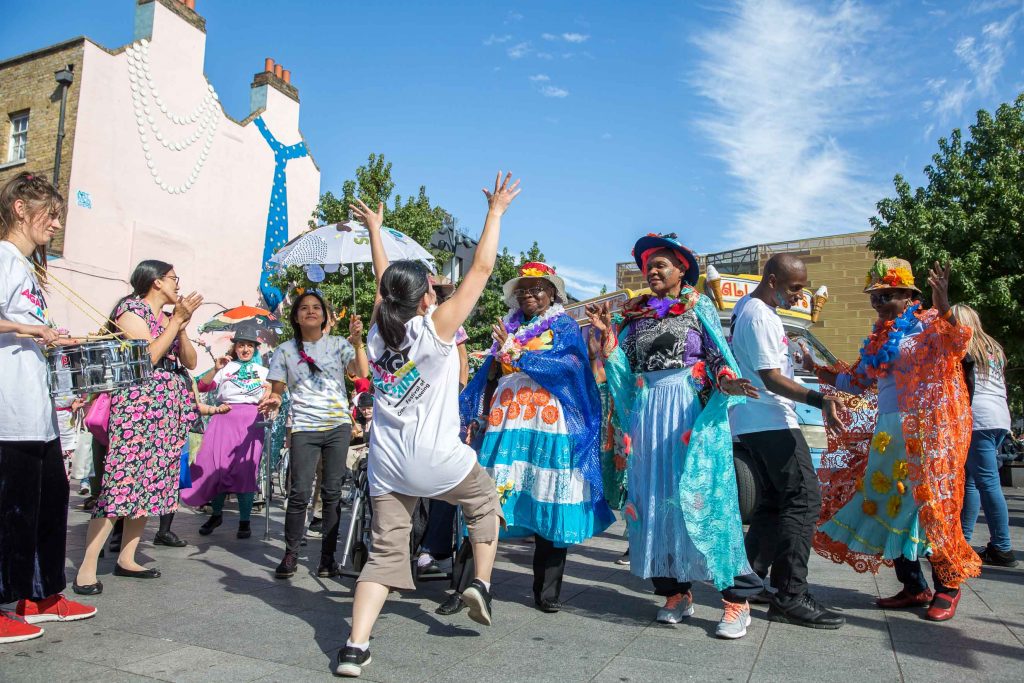 people dressed in bright clothing smilinga nd dancing in the street