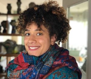 Portrait of Yolande, a woman with brown curly hair wearing a colourful scarf