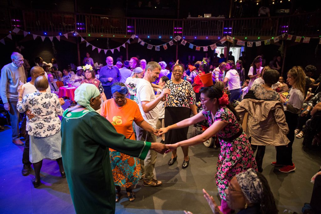 Many people in a hall dressed up and dancing together