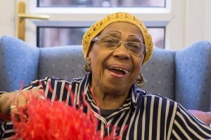 black woman laughing wearing a yellow knitted hat