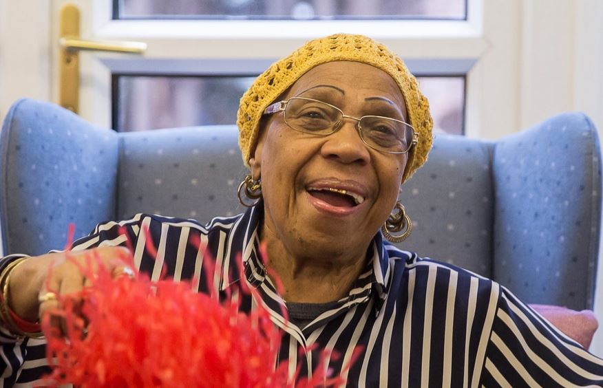 black woman laughing wearing a yellow knitted hat