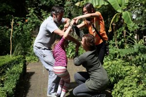 3 adults and a child playing together in a garden