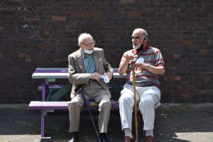 Two older men chatting on a bench.