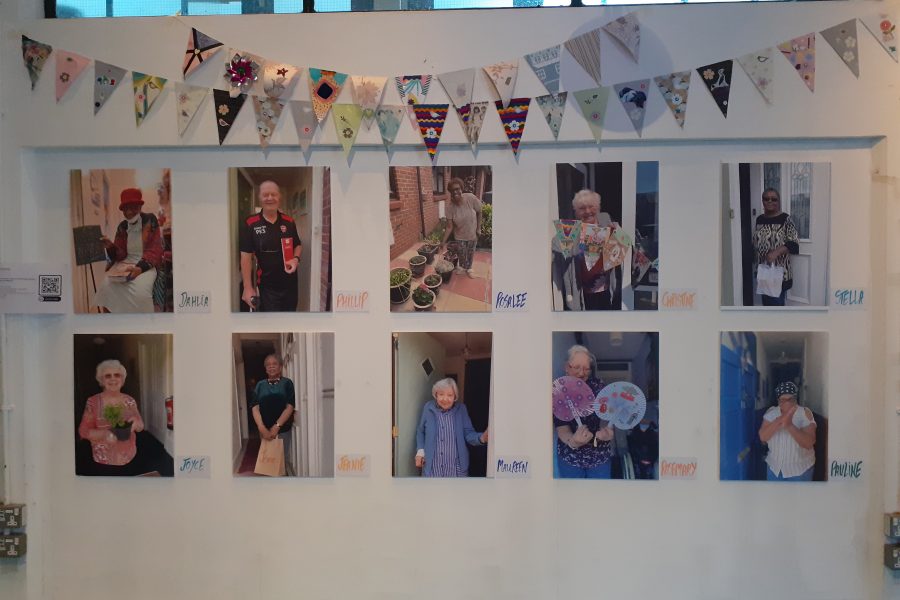 A white wall with photos of older people and colourful bunting hanging at the top